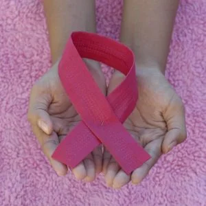 Mãos com laço rosa - Painel de câncer de mama e ovário hereditário